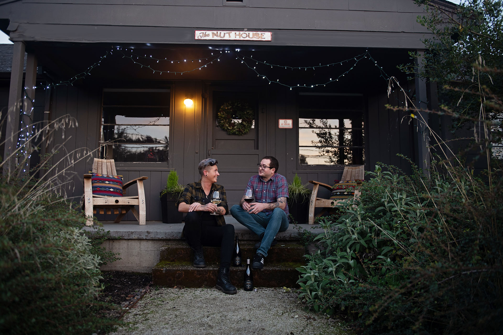 Two friends sitting in front of building with sign reading Nuthouse